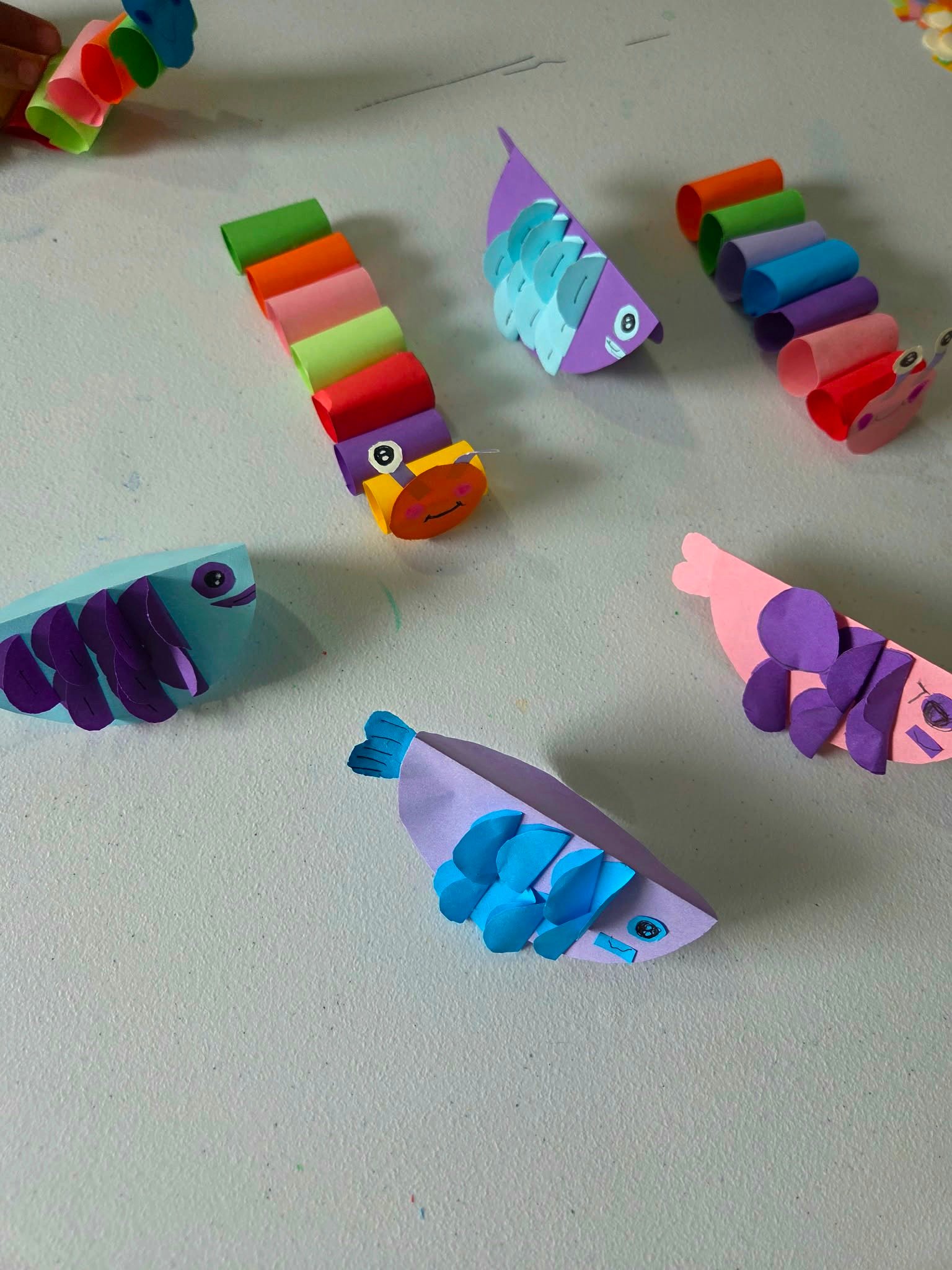 Student Paper Hand Craft — paper fish and caterpillar creations, close up